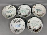 quatre assiettes en porcelaine ornées d'oiseaux et de fleurs, posées sur une table