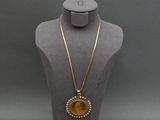 a gold necklace with a sunburst pendant on a mannequin