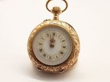 une montre de poche en or avec un cadran blanc sur une surface blanche