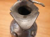 a silver vase with a bird on it on a wooden table