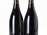 two bottles of wine sitting next to each other on a white surface