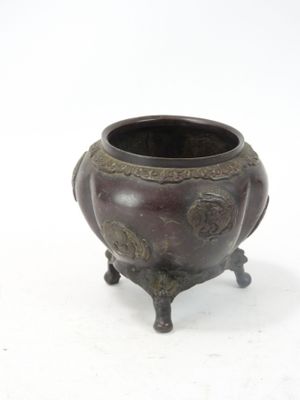 un petit pot en bronze muni d'une anse et posé sur un socle