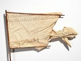 a small boat made of paper on a wooden stand