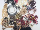 a pile of assorted necklaces and bracelets on a white surface