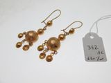 une paire de boucles d'oreilles dorées ornées de perles pendantes et d'une étiquette de prix