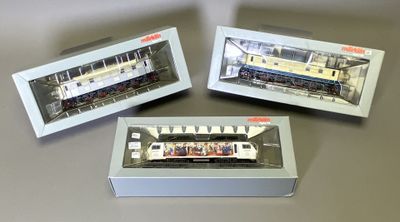 trois trains miniatures posés dans une boîte sur une table