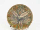 une assiette ornée d'un motif floral, posée sur un socle