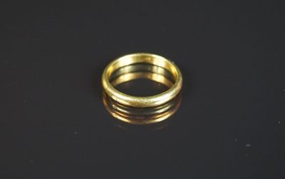 gros plan d'une bague en or sur une surface noire