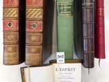 several old books are lined up on a shelf next to each other
