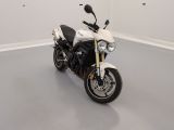 une moto blanche garée dans une pièce au sol gris