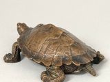 a small bronze turtle that is sitting on a table