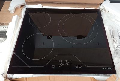 une plaque de cuisson en verre noir, dans une boîte posée sur une table