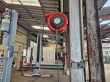une photo d'un tuyau rouge fixé à un poteau à l'intérieur d'un bâtiment