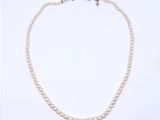 a close up of a white pearl necklace on a white background