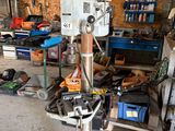 une perceuse posée sur un support dans un garage, avec des outils