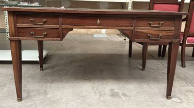un bureau en bois avec un plateau en verre et des chaises rouges