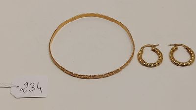 un gros plan sur un bracelet en or et une paire de boucles d'oreilles créoles
