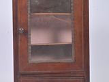a small wooden cabinet with a glass door on it