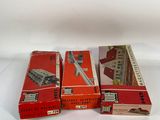 three boxes of old model trains sitting on top of a white surface