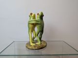 a statue of two frogs hugging each other on a glass table