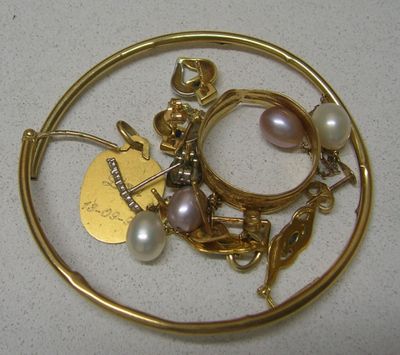 un gros plan sur une broche plaquée or ornée de perles et de breloques