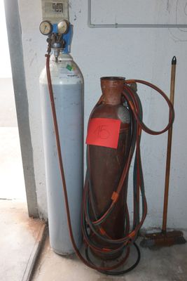 a gas bottle and a hose next to a fire extinguisher