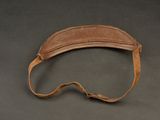 an old leather visor with a leather strap on a gray surface