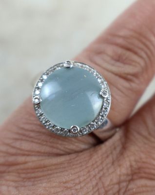 un gros plan de la main d'une personne tenant une bague sertie d'une pierre bleue