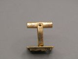 a close up of a gold tie bar on a gray surface