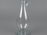 an empty glass vase with a handle sitting on a table