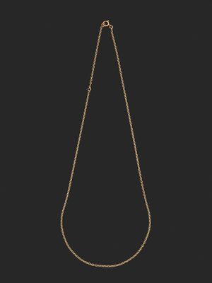 un collier en or dont la chaîne a été coupée en deux et qui est posé sur un fond noir