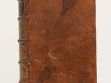 an old book sitting on top of a table next to a white wall
