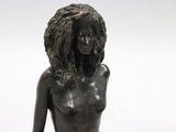 statue of a woman with long hair sitting on a white surface