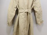 the trench coat is hanging on the wall next to the toilet