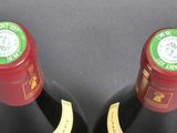 two bottles of red wine sitting next to each other on top of a table