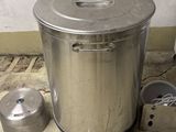 une grande casserole en métal posée par terre à côté d'une casserole plus petite