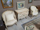 trois chaises et une table dans une pièce où sont accrochés des tableaux au mur