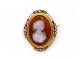 une broche antique en camée représentant une dame parée de perles, dans un cadre en or