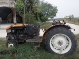 un tracteur qui est garé dans l'herbe près d'une grange