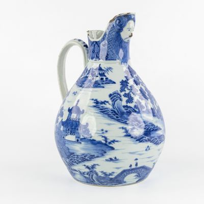 a blue and white pitcher with a landscape design on it