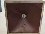 une horloge marron posée sur une table, sur fond blanc
