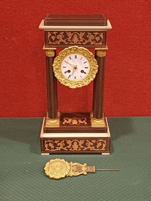 une horloge posée sur une table à côté d'une clé