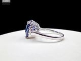 a close up of a blue sapphire and diamond ring on a white plate