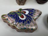 a butterfly shaped trinket sitting on a table next to a vase