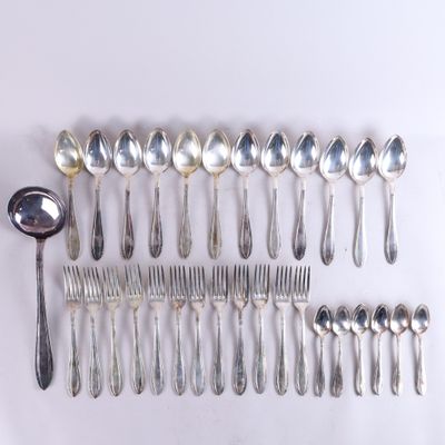 un grand nombre de cuillères et de fourchettes en argent disposées sur une table
