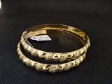 deux bracelets en or posés sur une surface noire, sur laquelle est fixée une étiquette