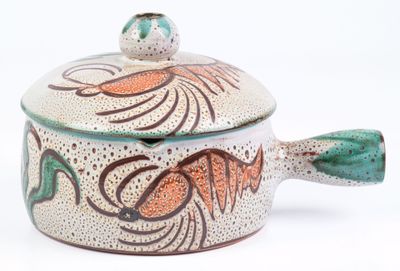 a small pot with a lid that has a fish design on it