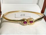 gold bangle with ruby stones and diamonds on display in a box