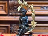 une statue en bronze représentant un garçon assis sur une table