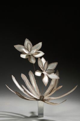 une sculpture métallique représentant des fleurs dans un vase posé sur une table